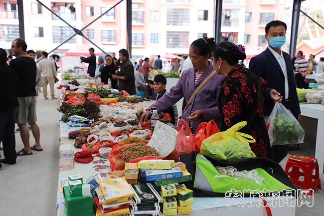 市场内的中草药摊位前，顾客正在产看其品质.jpg
