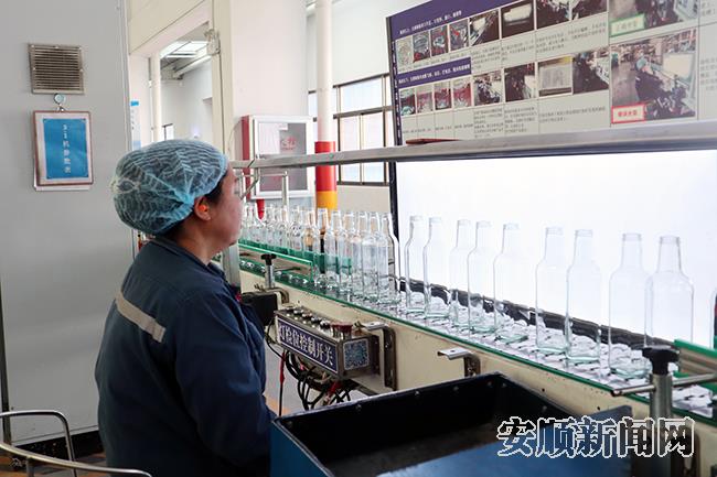 贵州华兴玻璃二期生产车间，一名女工在验瓶机生产线上认真检验产品.jpg