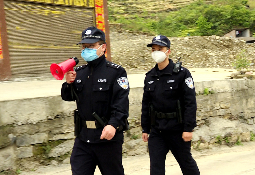 执勤民警用喇叭提醒村民注意防疫不放松.jpg